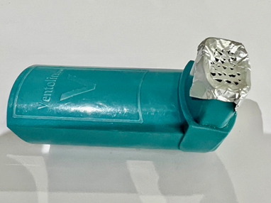 A blue asthma inhaler with mouthpiece covered in tin foil with holes.